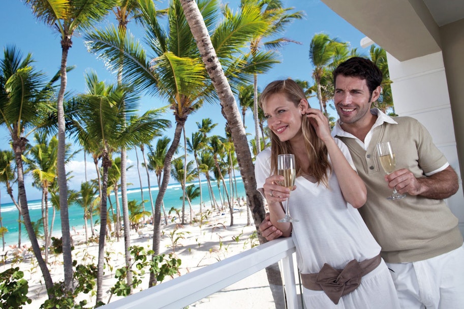 Koppel op een balkon met uitzicht palbomen en zee Punta Cana
